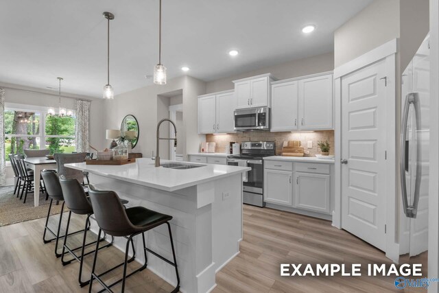 303 Keller Dr, Hazel Green, AL 35750 - kitchen with appliances with stainless steel finishes, a sink, decorative backsplash, a kitchen breakfast bar, and white cabinetry