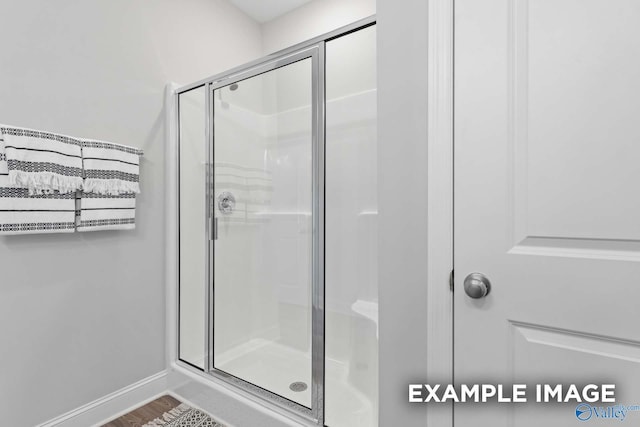 bathroom with wood-type flooring and an enclosed shower