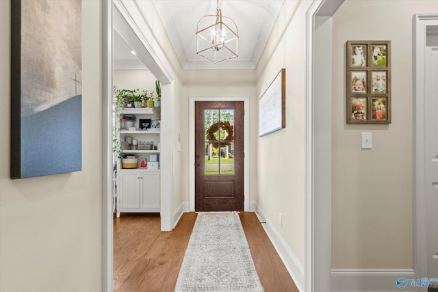 entrance foyer with a chandelier, crown molding, and light hardwood / wood-style floors