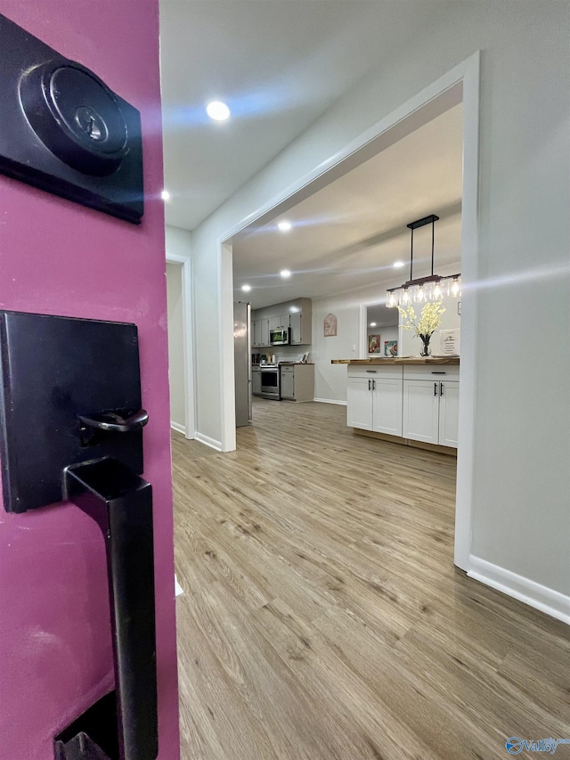 interior space featuring light wood-style flooring, baseboards, and recessed lighting