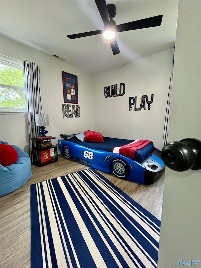 bedroom with wood finished floors, a ceiling fan, and visible vents