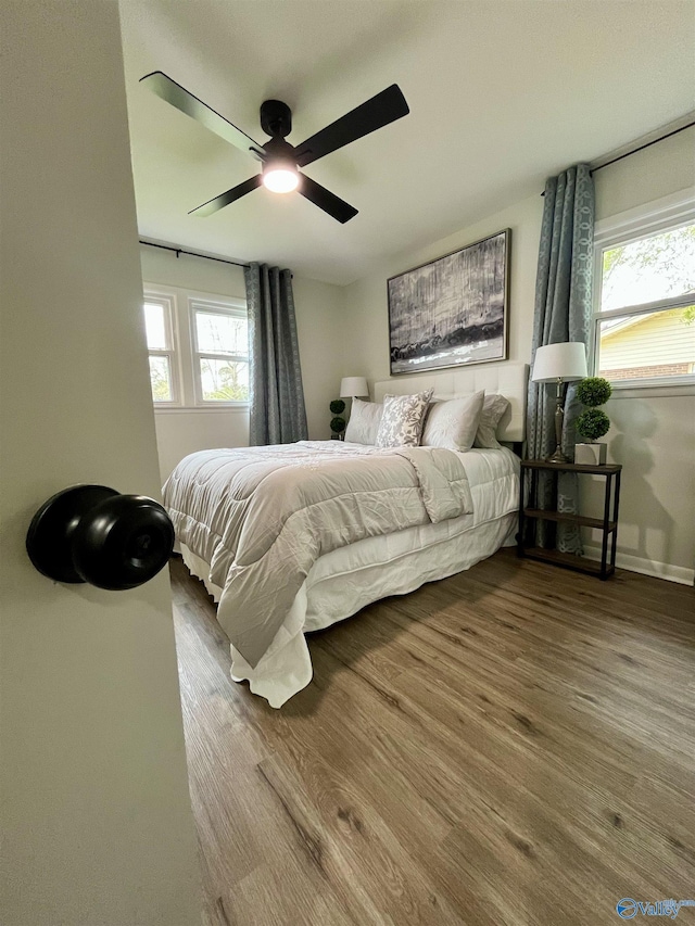 bedroom featuring a ceiling fan, wood finished floors, and multiple windows