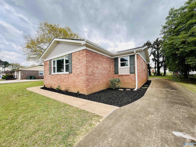 view of property exterior featuring crawl space, a yard, concrete driveway, and brick siding
