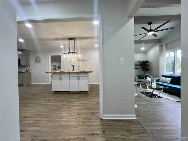 kitchen featuring wood finished floors, baseboards, a ceiling fan, and white cabinets