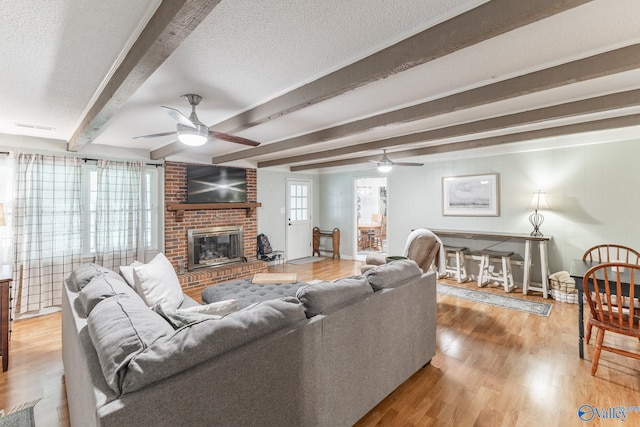 43 Terry Ln, Trinity, AL 35673 - living area featuring ceiling fan, wood finished floors, beamed ceiling, a brick fireplace, and a textured ceiling