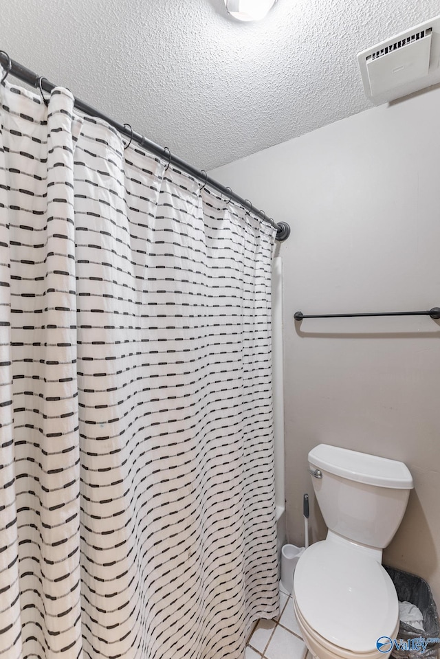 43 Terry Ln, Trinity, AL 35673 - bathroom featuring a textured ceiling, a wall unit AC, toilet, tile patterned floors, and shower / bath combination with curtain