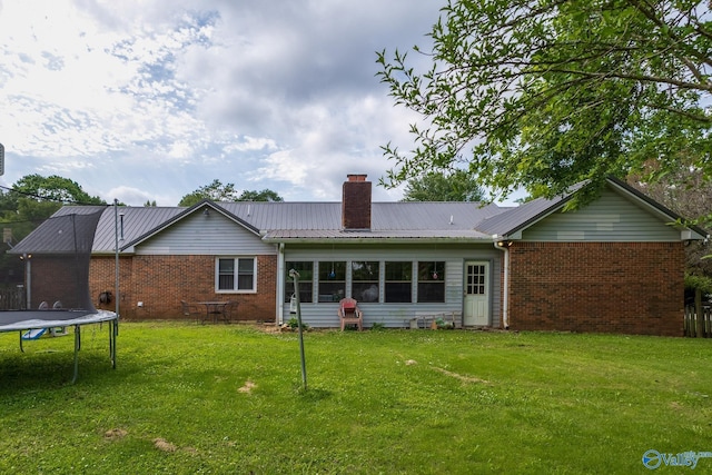 43 Terry Ln, Trinity, AL 35673 - rear view of property featuring a trampoline, brick siding, a chimney, and a yard