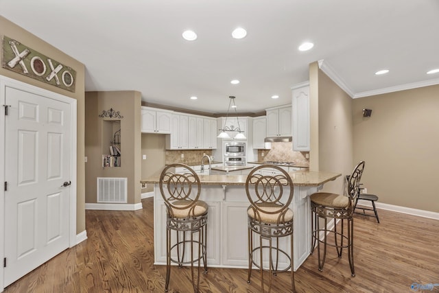 230 Knotting Pl, Madison, AL 35758 - kitchen featuring stainless steel appliances, light stone countertops, wood finished floors, white cabinetry, and backsplash