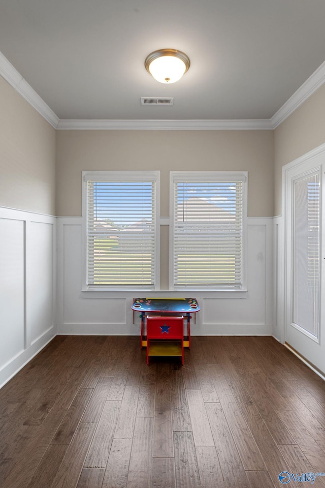 28622 Paseo Rd, Madison, AL 35756 - empty room with a decorative wall, crown molding, wood finished floors, a wainscoted wall, and healthy amount of natural light