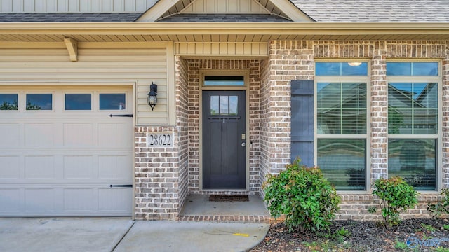 28622 Paseo Rd, Madison, AL 35756 - property entrance featuring roof with shingles, an attached garage, brick siding, board and batten siding, and driveway