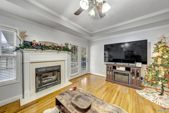 living room with a wealth of natural light, crown molding, ceiling fan, and light wood-type flooring