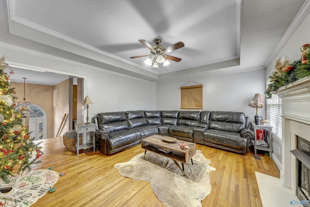 living room featuring a tray ceiling, crown molding, ceiling fan, and light wood-type flooring