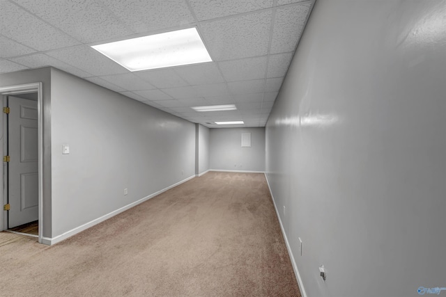 basement featuring a paneled ceiling and light colored carpet