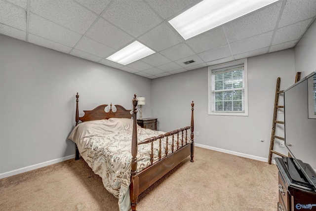 bedroom featuring light carpet and a drop ceiling