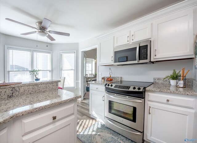 kitchen with white cabinets, light wood finished floors, light stone counters, and stainless steel appliances