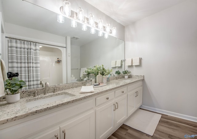 full bath with wood finished floors, a sink, visible vents, baseboards, and double vanity