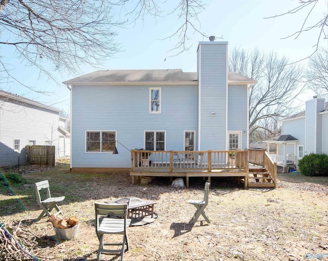 rear view of property featuring a fire pit, a deck, and a chimney