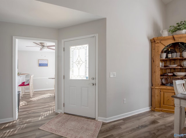 foyer entrance with ceiling fan, baseboards, and wood finished floors