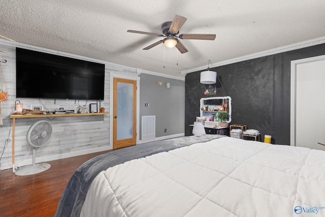 bedroom with a textured ceiling, ornamental molding, visible vents, wood finished floors, and baseboards
