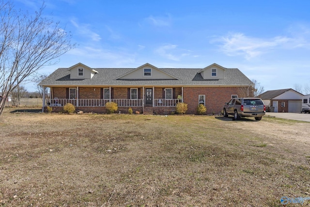 view of front of property featuring brick siding, a front yard, a porch, and a shingled roof