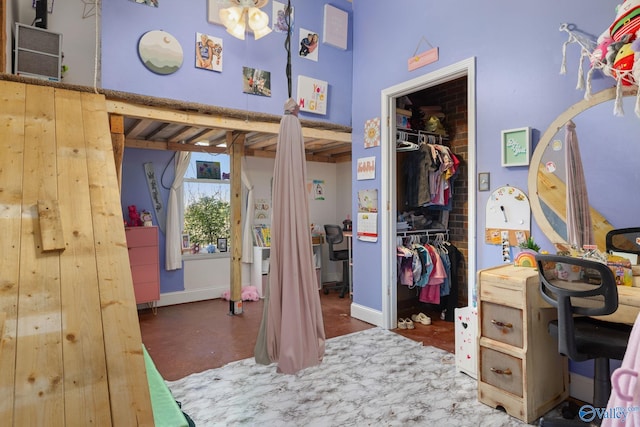 bedroom featuring a closet, baseboards, a walk in closet, and a high ceiling