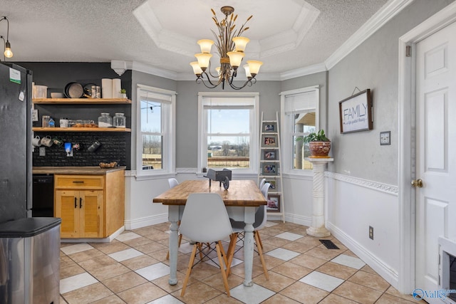 dining area with crown molding, a raised ceiling, a notable chandelier, and a textured ceiling