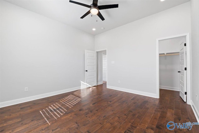 unfurnished bedroom with ceiling fan, dark hardwood / wood-style flooring, a spacious closet, and a closet