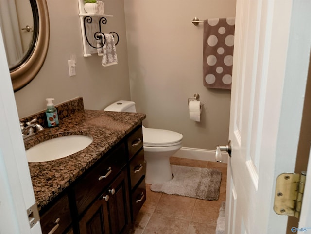 bathroom featuring tile patterned flooring, vanity, baseboards, and toilet