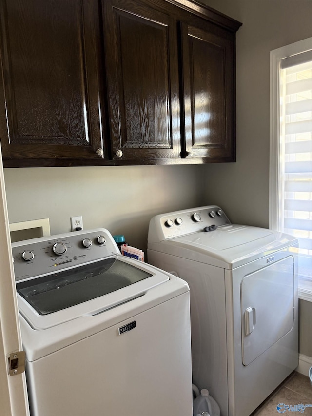 laundry area featuring light tile patterned floors, separate washer and dryer, and cabinet space