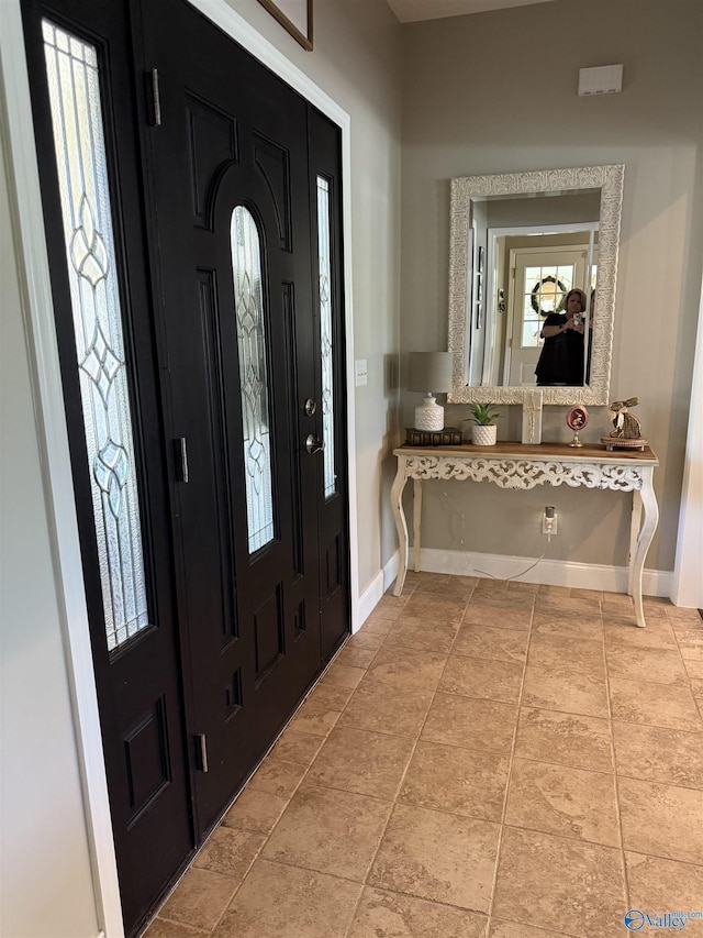 entrance foyer with a healthy amount of sunlight, light tile patterned floors, and baseboards