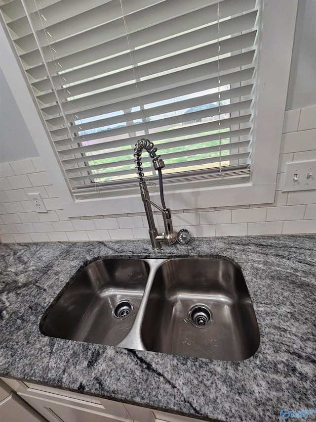 room details with a sink, decorative backsplash, and stone countertops