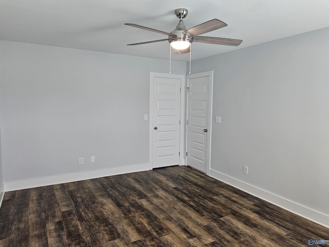 empty room with a ceiling fan, baseboards, and dark wood-style flooring