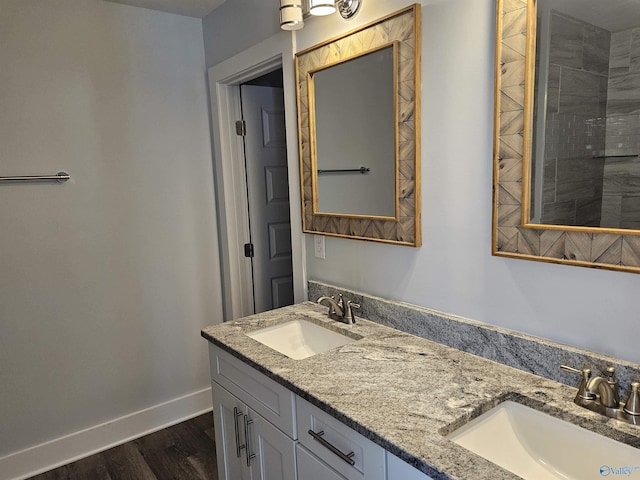 bathroom featuring double vanity, wood finished floors, baseboards, and a sink