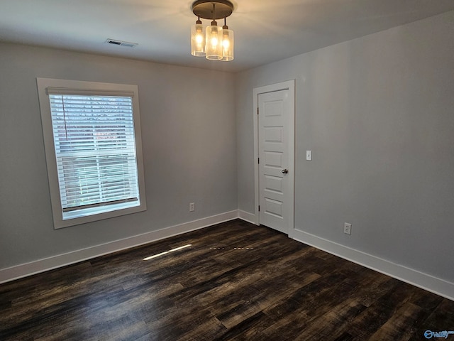 empty room with dark wood finished floors, baseboards, and visible vents