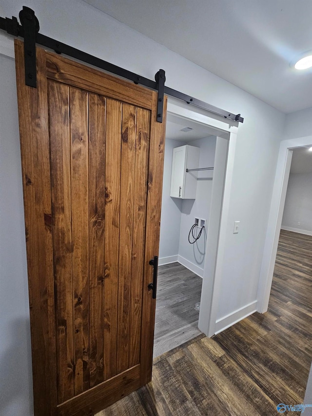 interior details with a barn door, wood finished floors, and baseboards