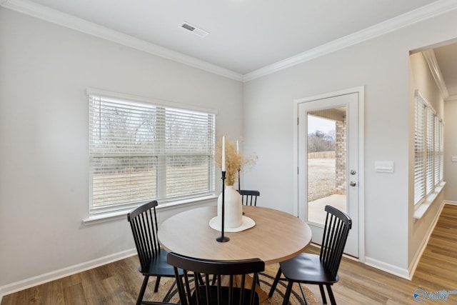 dining area with hardwood / wood-style flooring, crown molding, and plenty of natural light