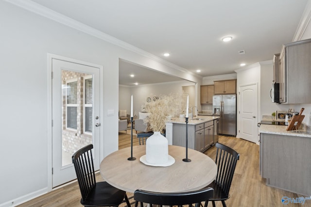 dining space featuring ornamental molding, sink, and light wood-type flooring