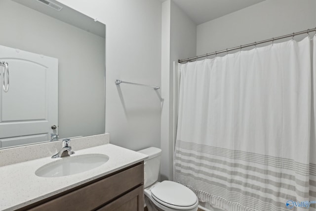 bathroom with walk in shower, vanity, and toilet