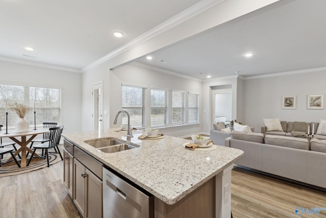 kitchen with dishwasher, sink, light stone counters, a center island with sink, and light wood-type flooring