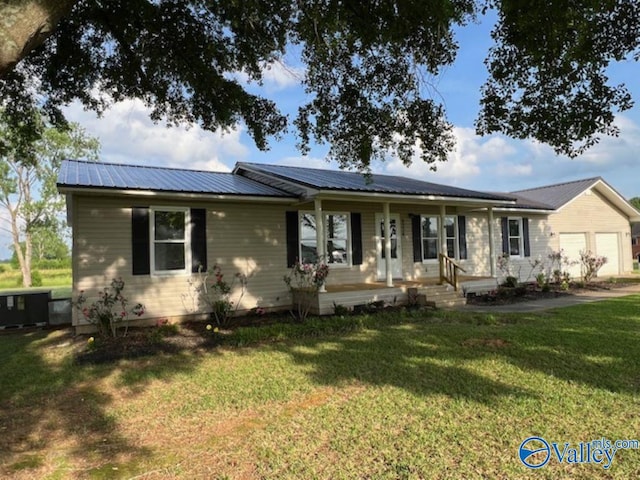 ranch-style house featuring a garage, a front yard, roof mounted solar panels, covered porch, and metal roof