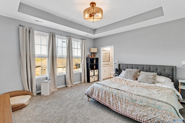 carpeted bedroom with ensuite bath, visible vents, baseboards, and a raised ceiling