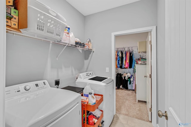 laundry room featuring light tile patterned floors, washing machine and dryer, light colored carpet, and laundry area
