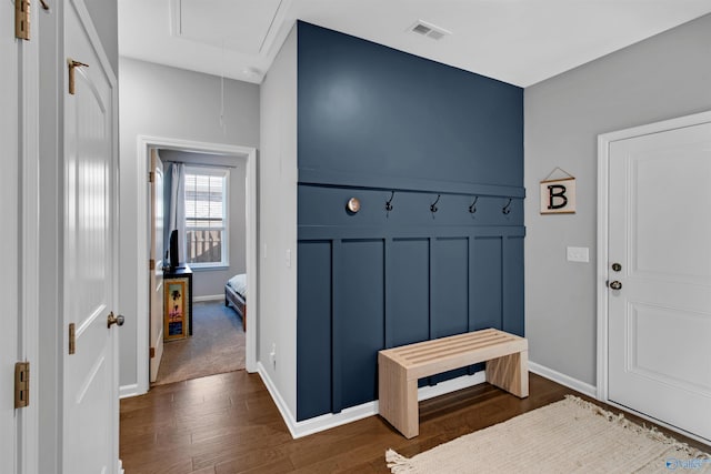 mudroom with dark wood-type flooring, visible vents, baseboards, and attic access