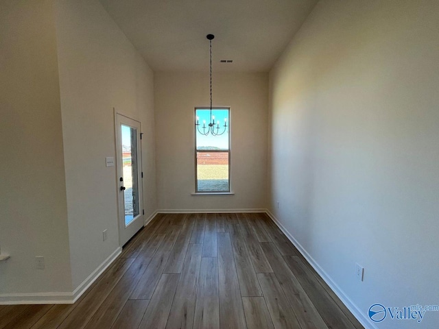 unfurnished dining area featuring hardwood / wood-style floors and a chandelier