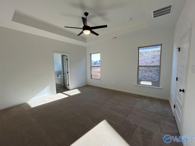 unfurnished room with ceiling fan, dark carpet, a tray ceiling, and ornamental molding