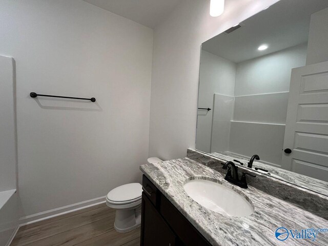 bathroom featuring toilet, vanity, walk in shower, and hardwood / wood-style flooring