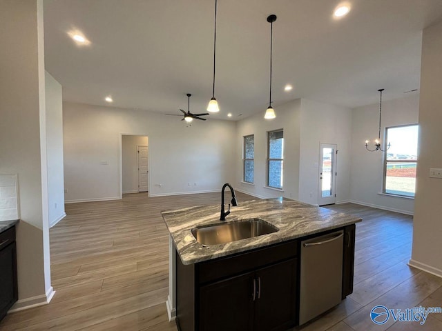 kitchen with a center island with sink, light wood-type flooring, dishwasher, stone countertops, and sink