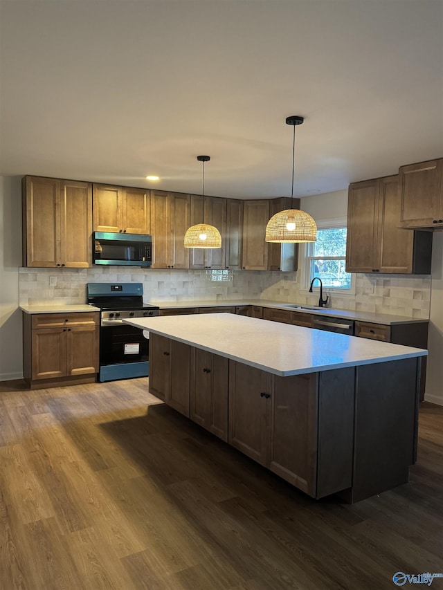 kitchen with hanging light fixtures, sink, stainless steel range with electric cooktop, and dark hardwood / wood-style flooring