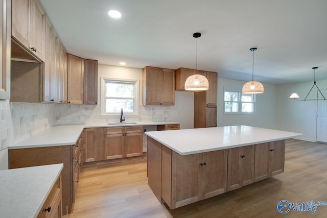 kitchen featuring tasteful backsplash, sink, a kitchen island, and light wood-type flooring