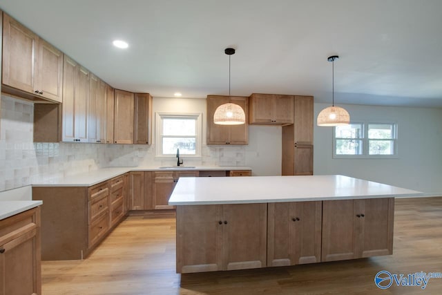 kitchen featuring a center island, sink, hanging light fixtures, and light wood-type flooring